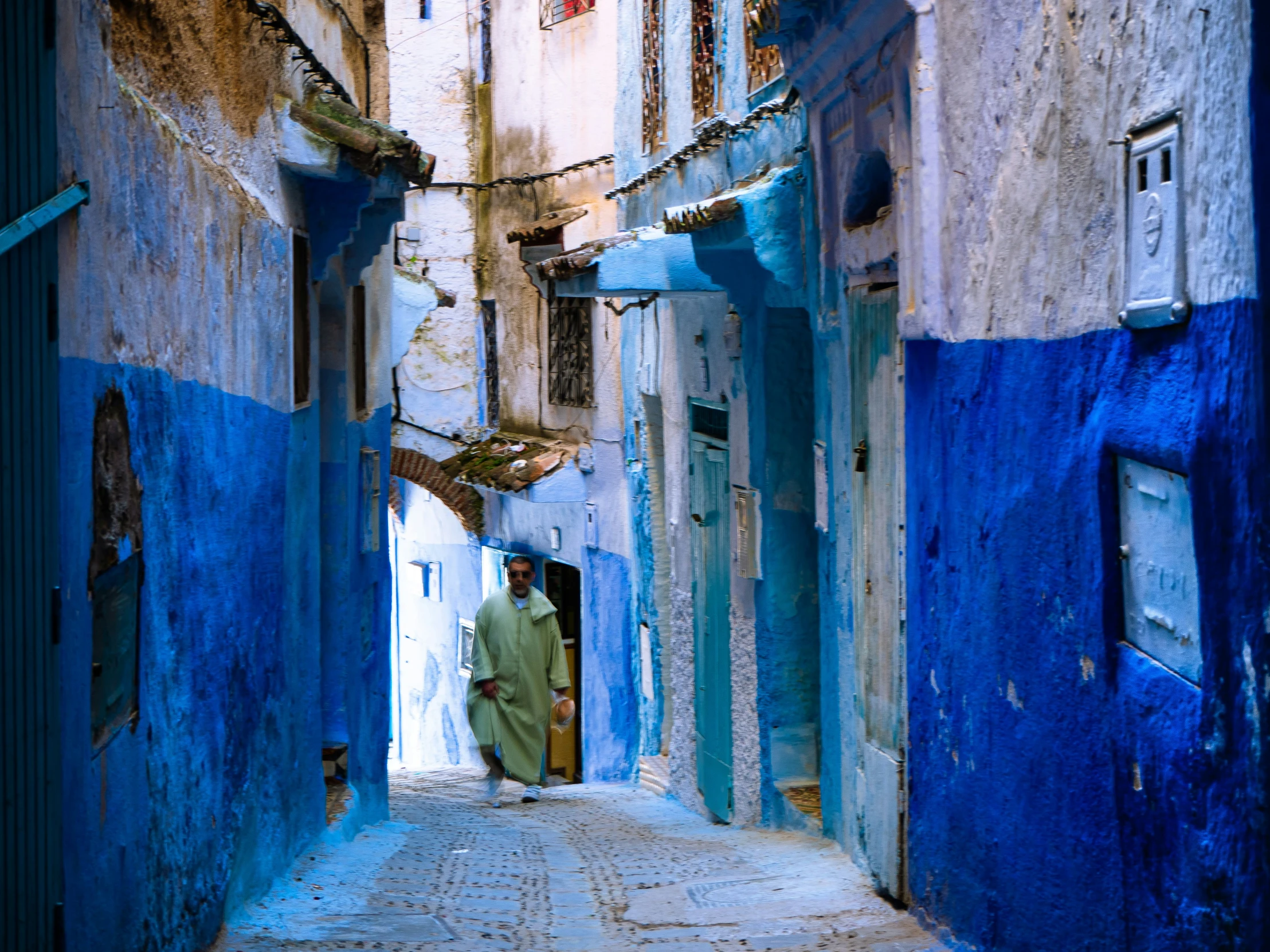 a man walking down a narrow alleyway between old buildings