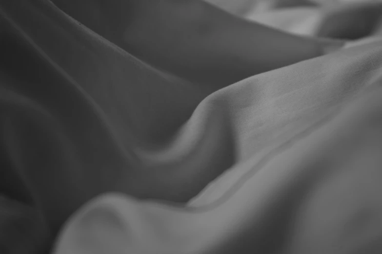 black and white pograph of cloth on bed sheets