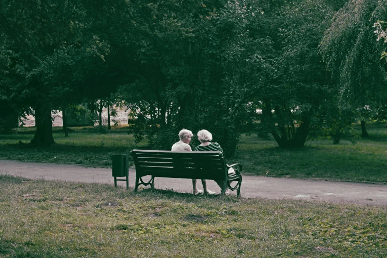 two elderly people are sitting on a bench