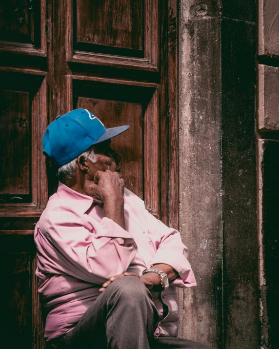 a man is sitting outside while talking on his phone