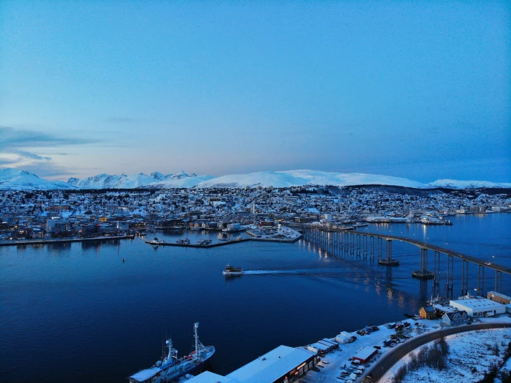 snowy winter scene from top of hill overlooking lake and bridge