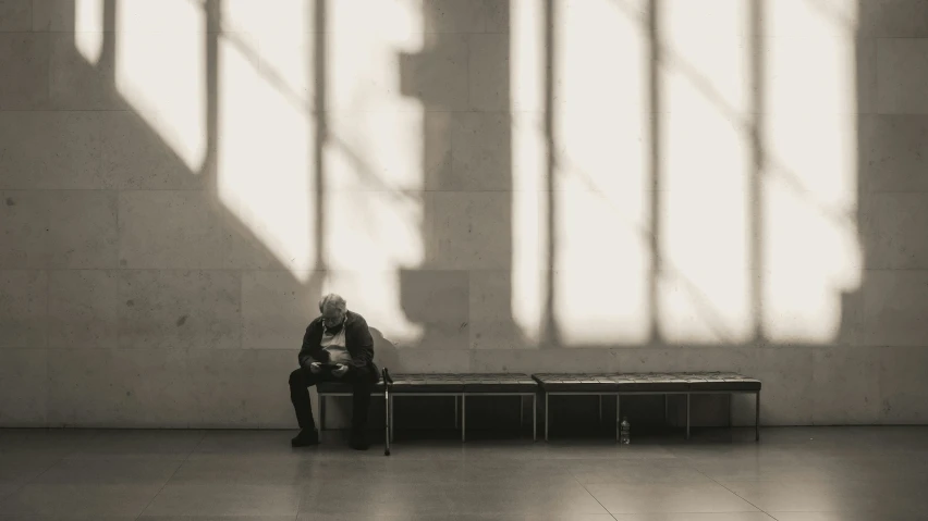 an elderly man sits alone as the sun reflects off his windows