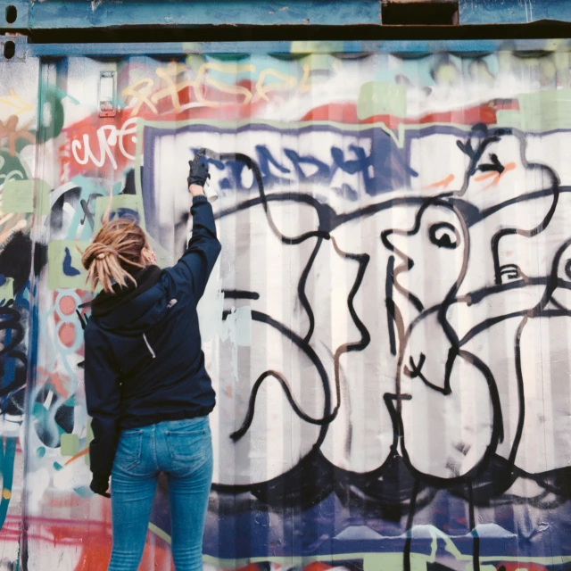 a woman reaching up for the sky in front of graffiti