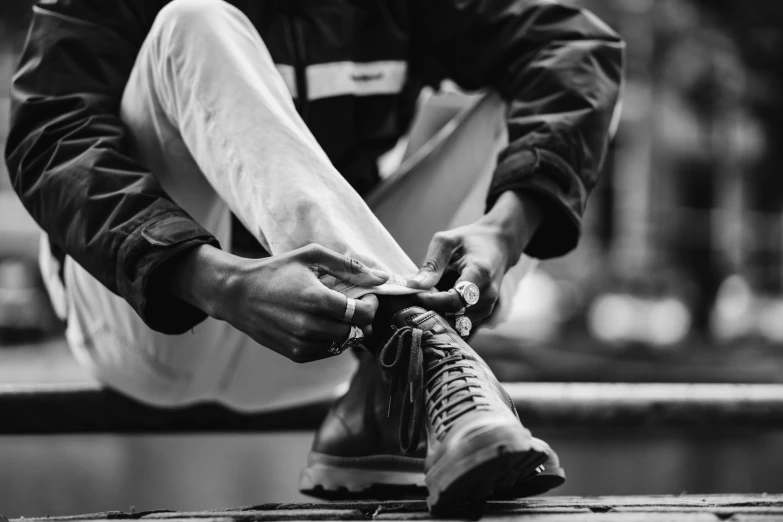 a black and white po of someone tying up his shoe