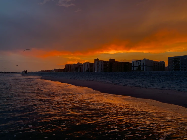 the beach and shoreline at sunset in a city