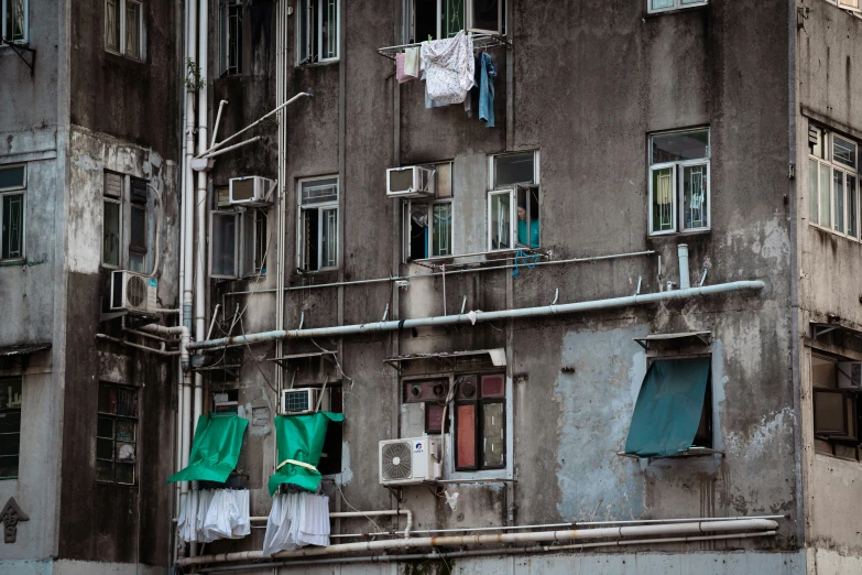 several green clothes are hanging from a gray apartment building