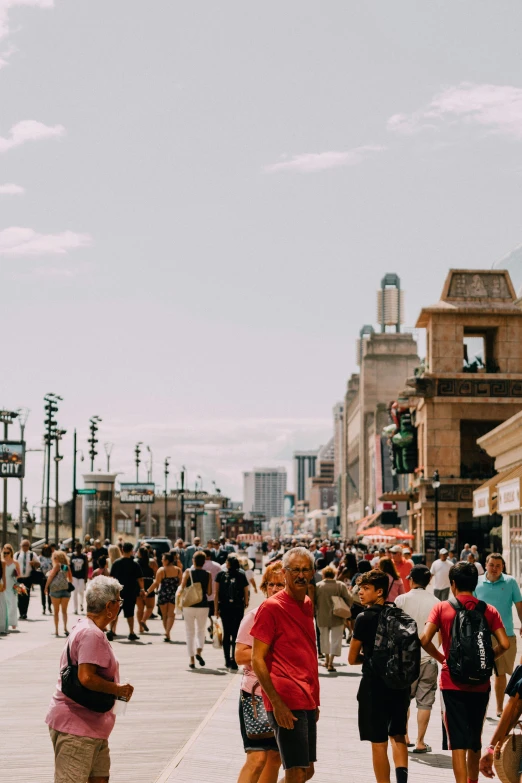 group of people standing in a plaza of old buildings and on the boardwalk