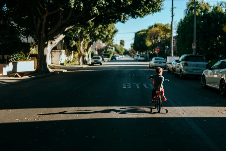 a little boy is riding his bike down the street