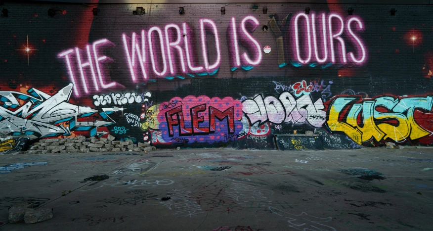 a brick wall covered in graffiti that says the world is ourss