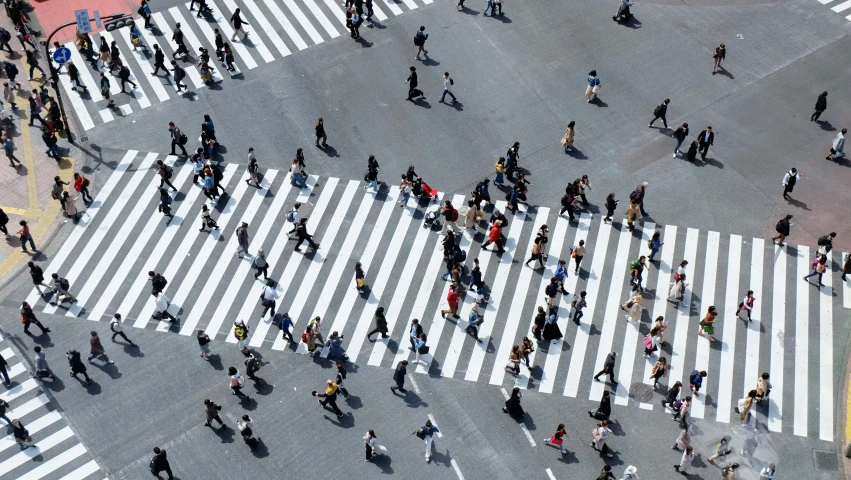 a crowd of people crossing a street with ze crossing stripes