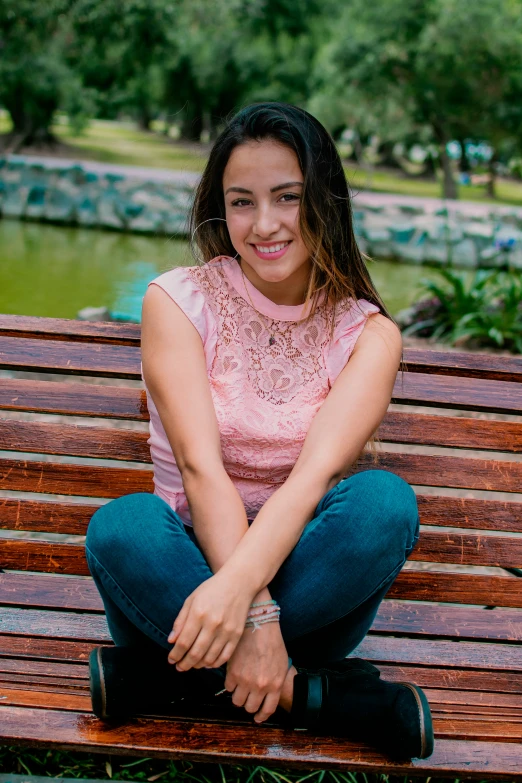 a beautiful young woman sitting on top of a wooden bench