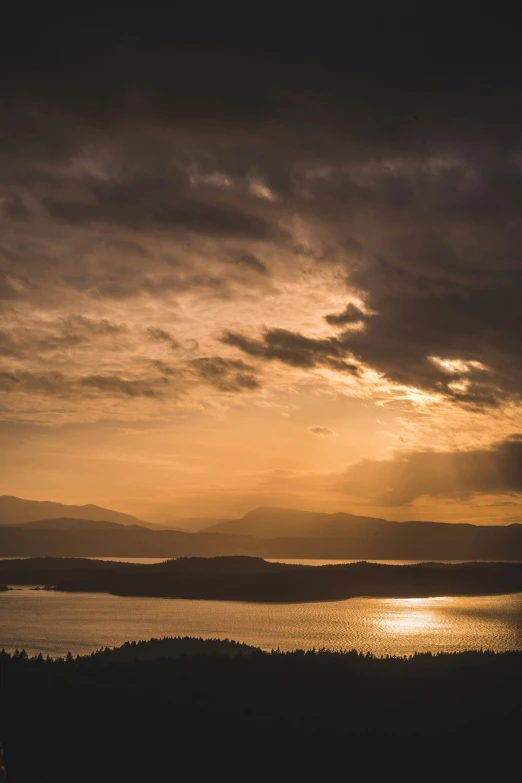 a view of a lake and some hills at sunset