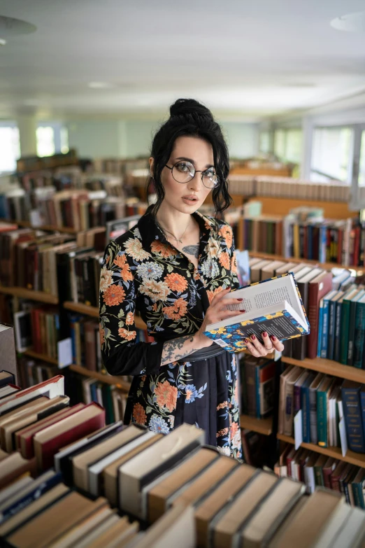 a woman is looking through an open book in the liry