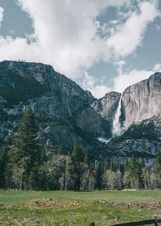 a waterfall cascades into the mountains of a green pasture