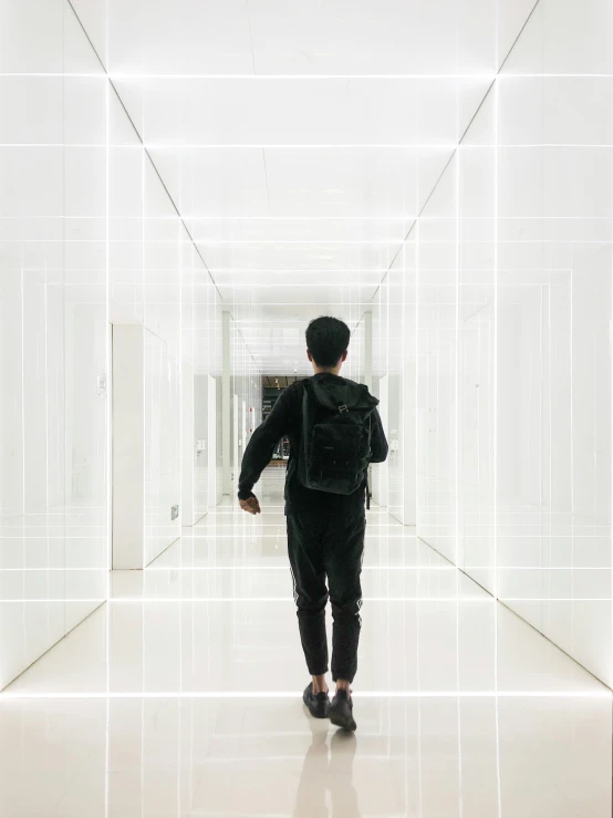 a man is walking down a hallway in front of some white squares