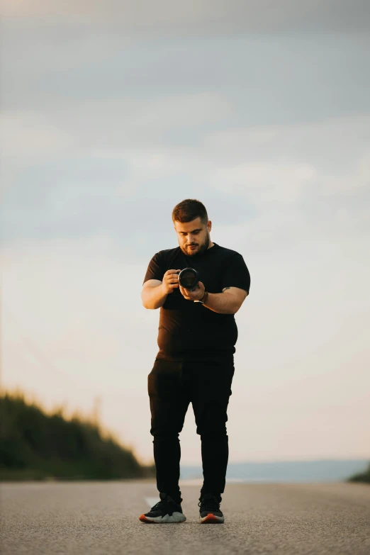 man standing on the side of road holding his camera