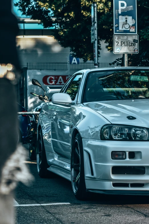 a white car with a chrome hood parked in front of a parking sign