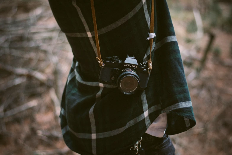 a person holding onto a camera while standing in the woods