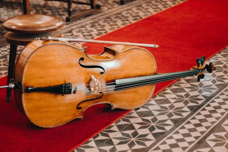 a violin rests upright on a red carpet