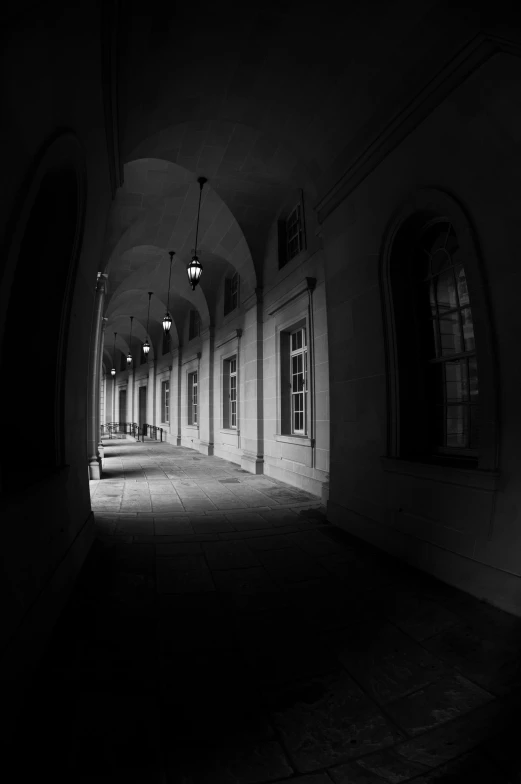 a dark alley has arched doorways, a ceiling with white tiles and windows