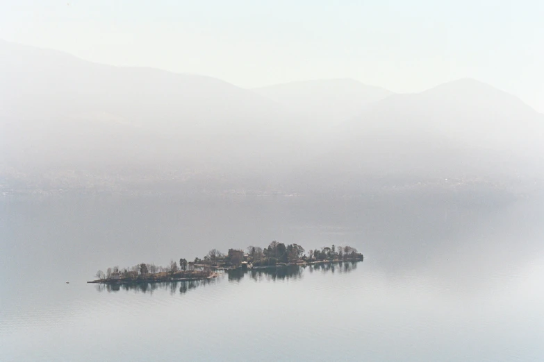 a small island sitting on a lake surrounded by mountains