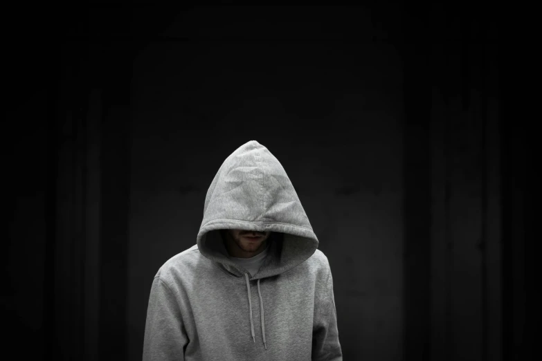 a hooded person wearing a hoodie and standing in the dark