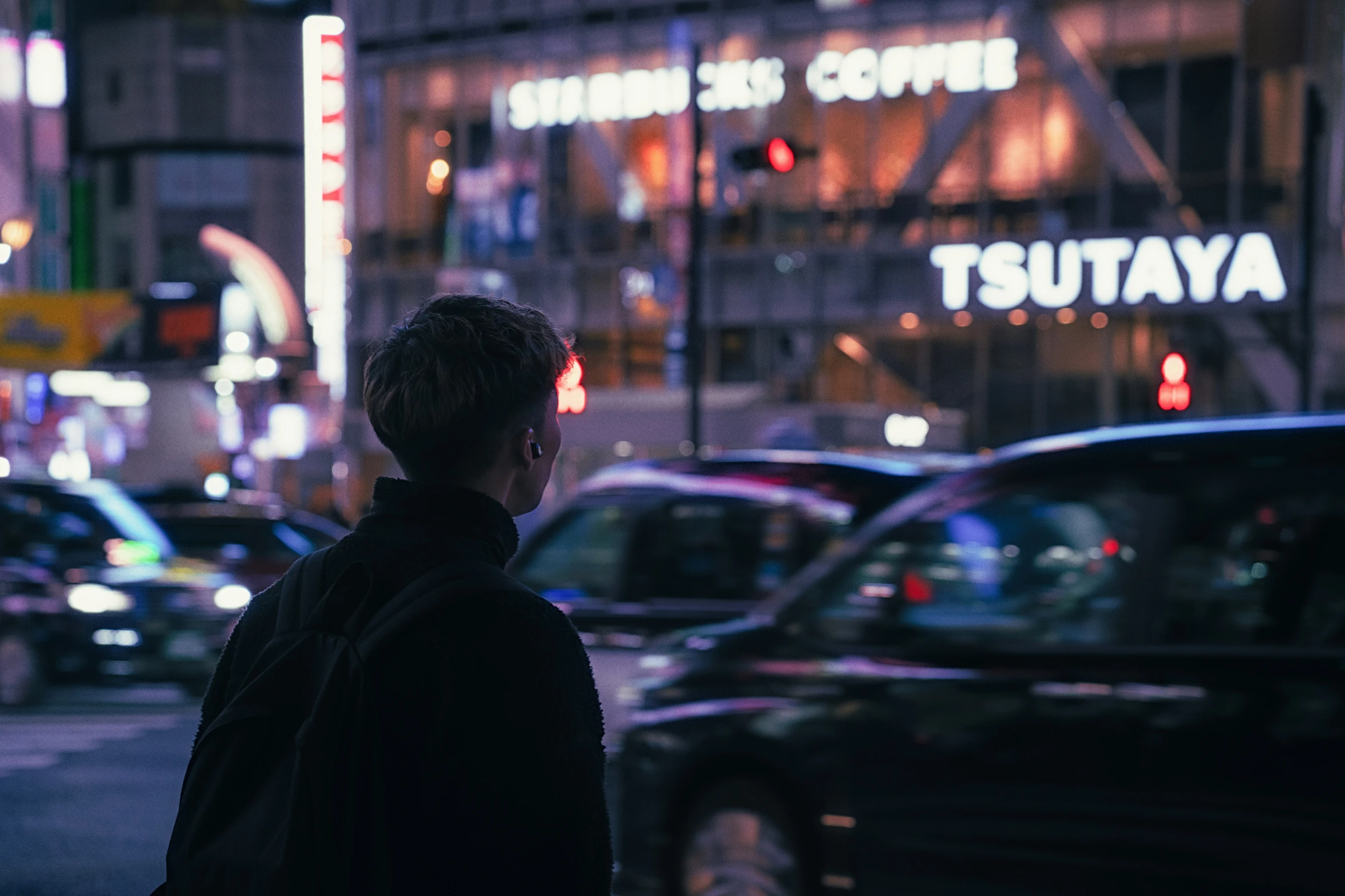 a man standing in the street on a corner with cars in front of him