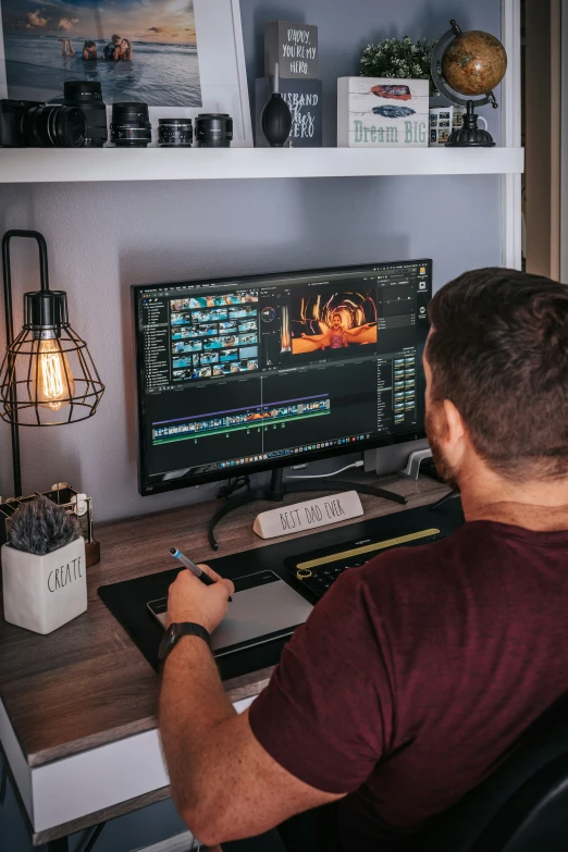 a man is sitting in front of the computer monitor with his back turned to the camera