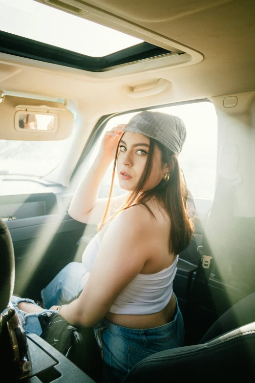 the woman in the car has a cap on and wears a tank top