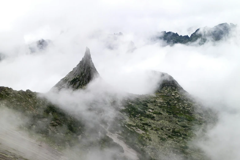 a mountain with clouds and fog moving in from top