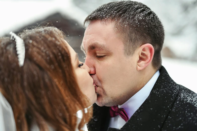 a young man kissing his girlfriend in the snow