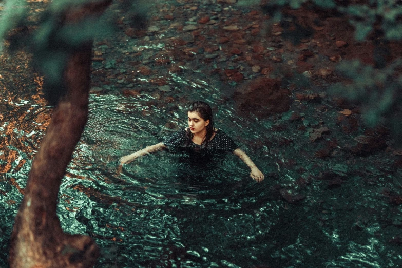 a woman is swimming in a pool with trees nearby