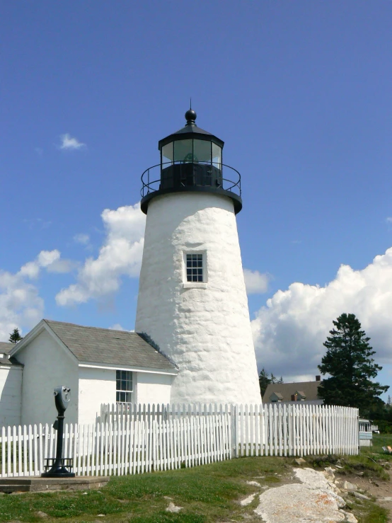 there is a light house behind a picket fence