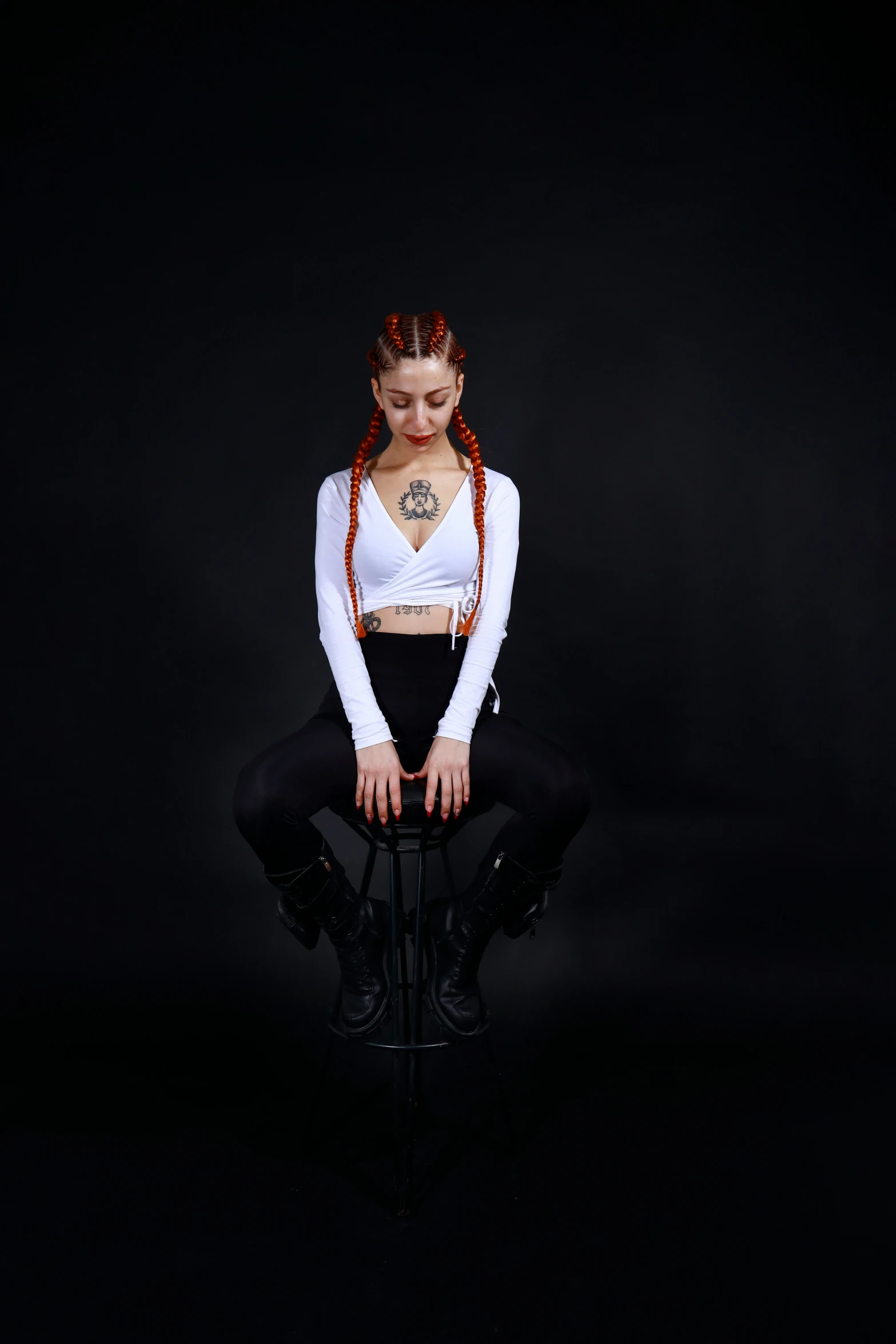 a girl sitting on a chair wearing tight black pants