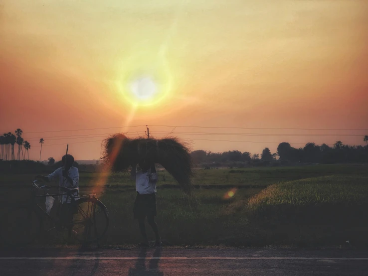 people on a bike under an umbrella as the sun sets