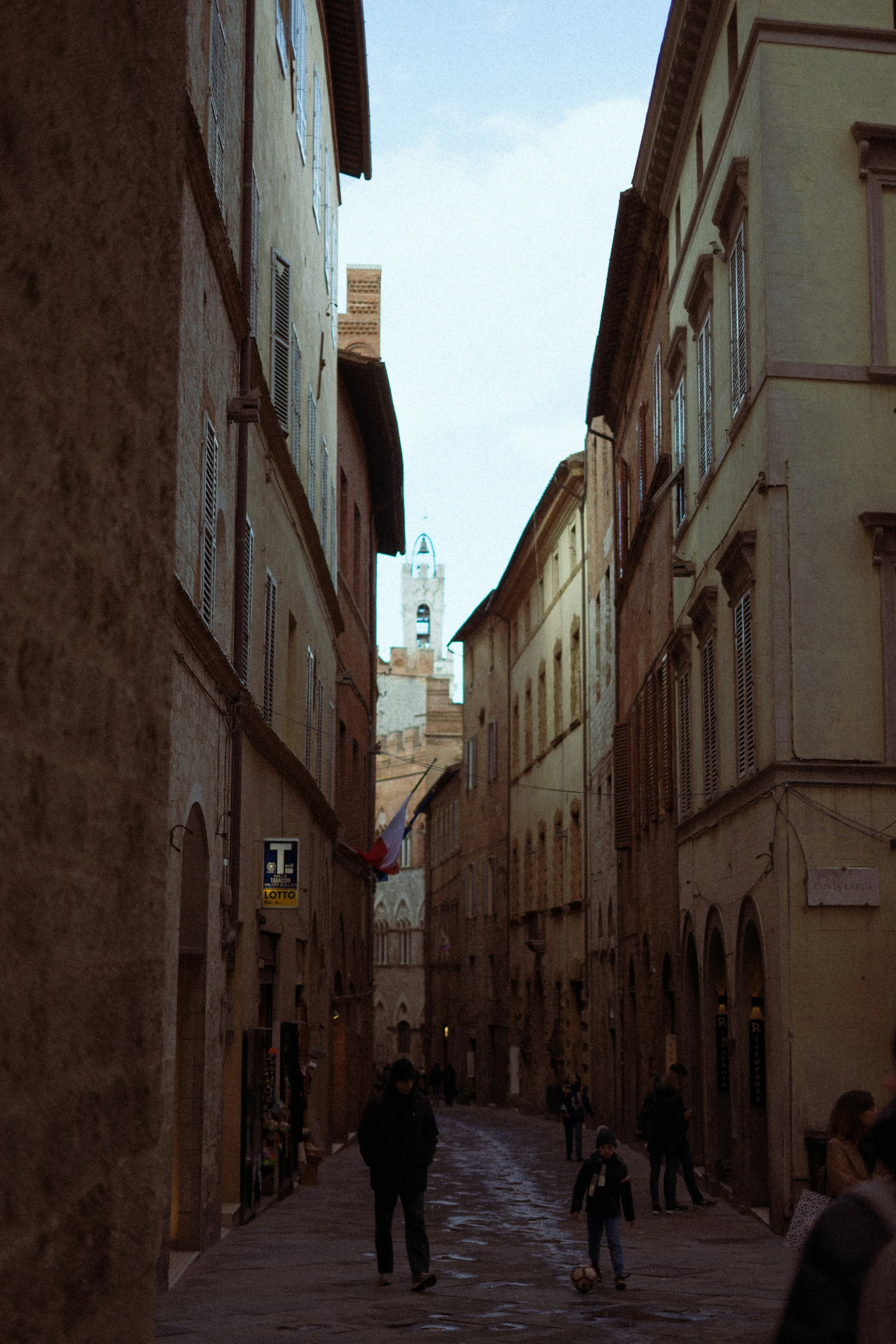 some people walking down a dark street and a church tower