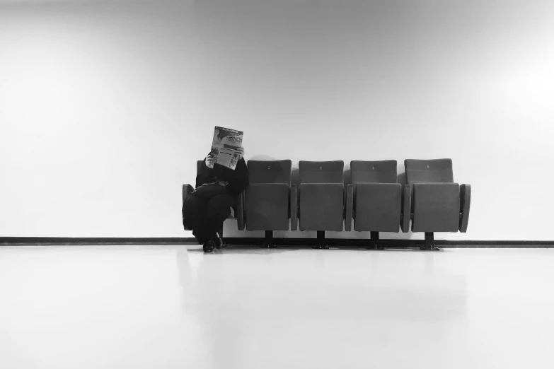 an old black and white po of a person sitting on a bench reading a book