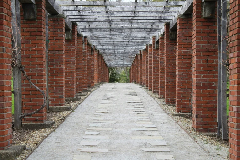 a long walkway covered in brick with trees