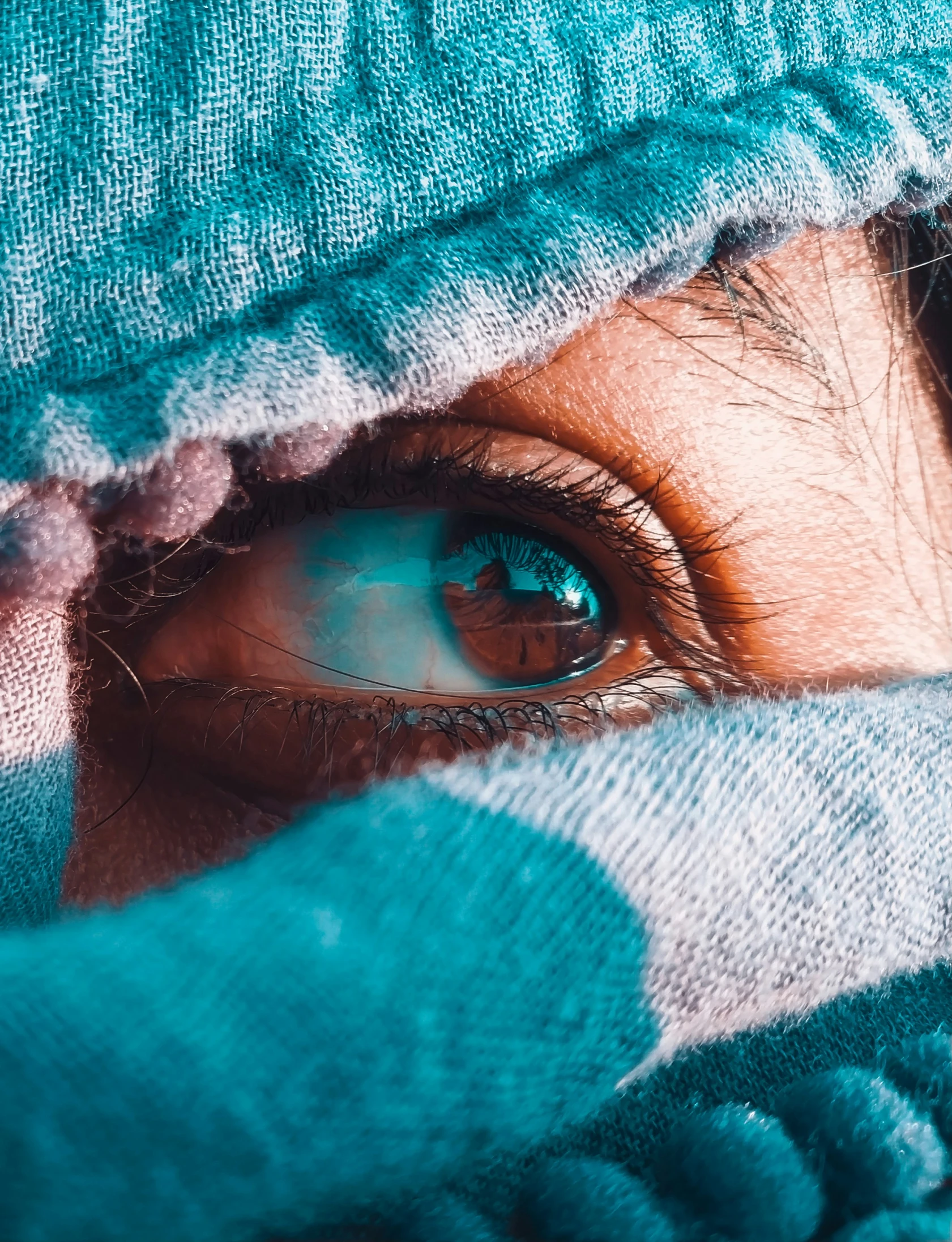 an eye pokes out of the green material on top of a towel