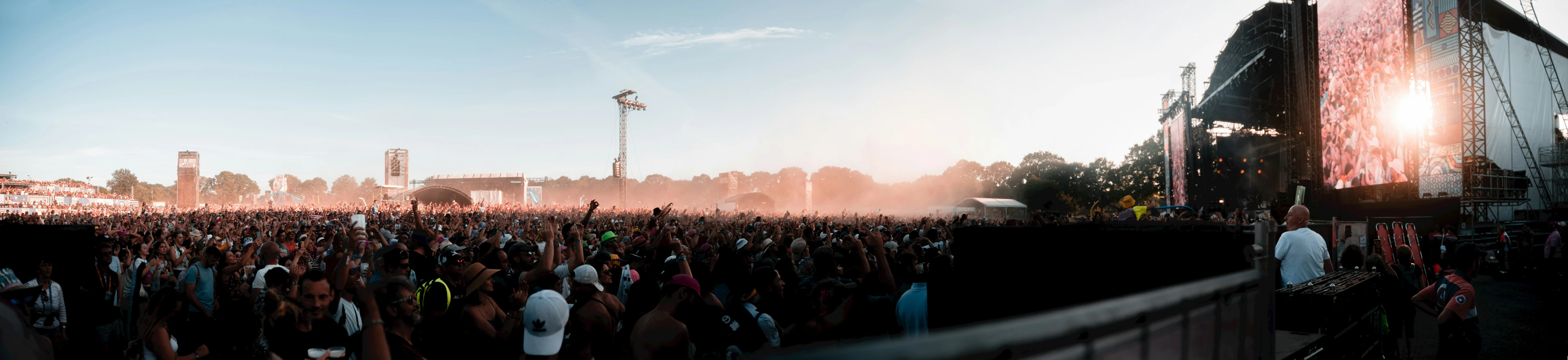 a large crowd at an outdoor concert near a tall building