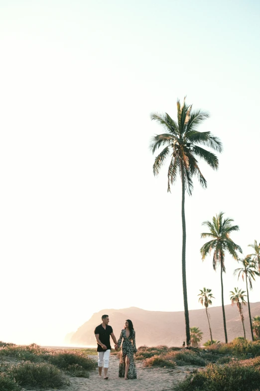 a couple holding hands on a dirt road near the beach