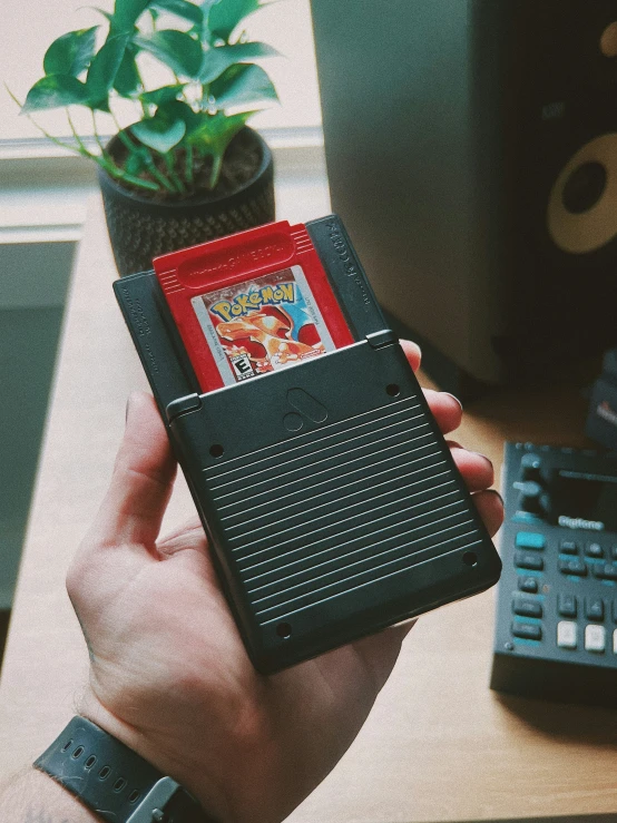 a nintendo game system is held up in one hand by someone's hand