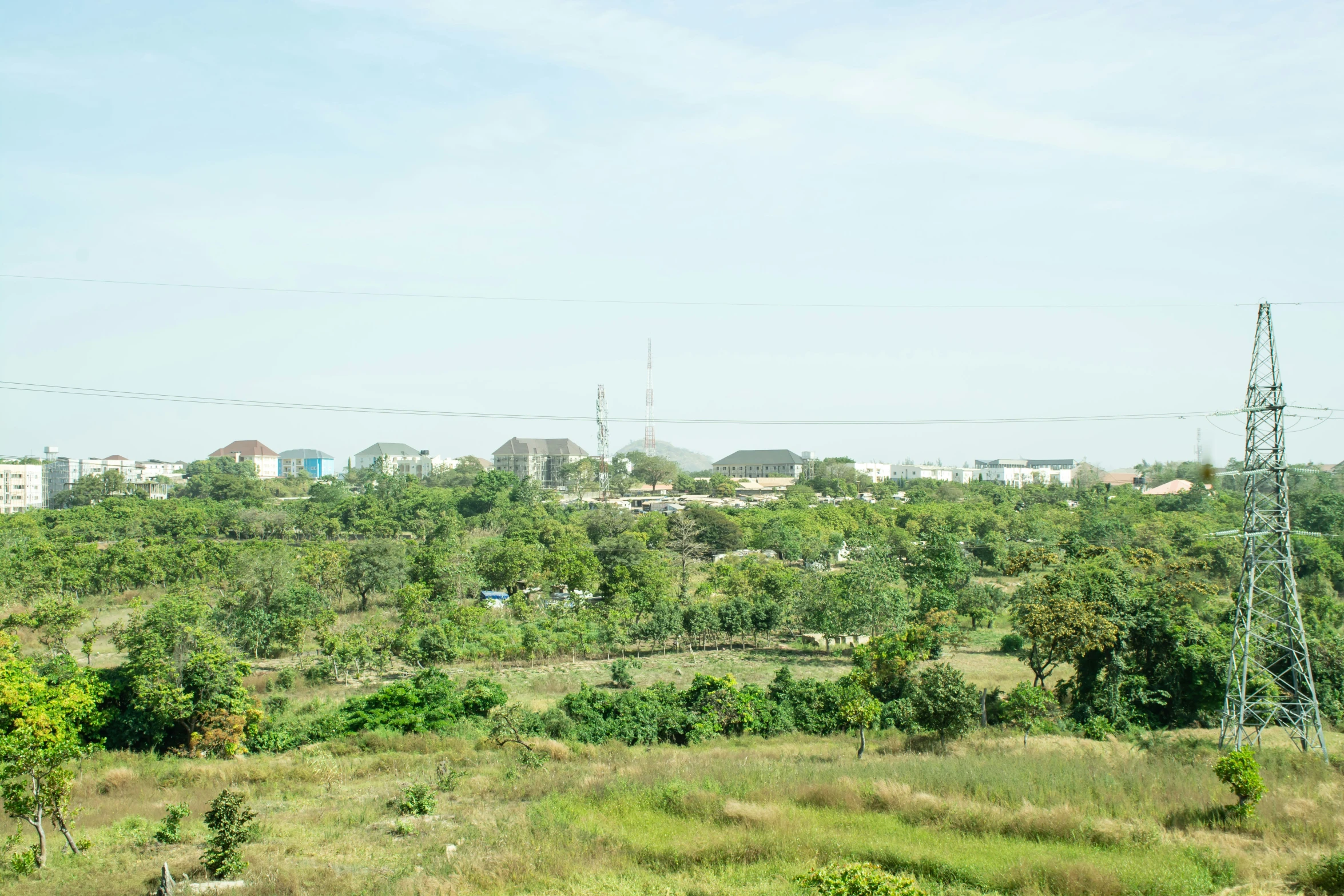 a view of a grassy land with houses and trees in the distance