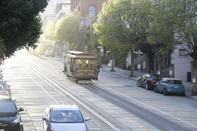 the tram car goes down the street as it makes its way up the hill