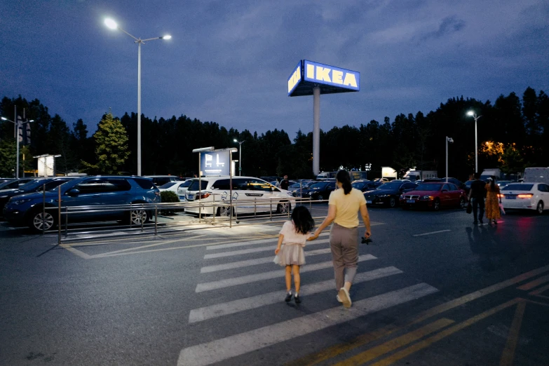 a family walking across a crosswalk in a parking lot at dusk