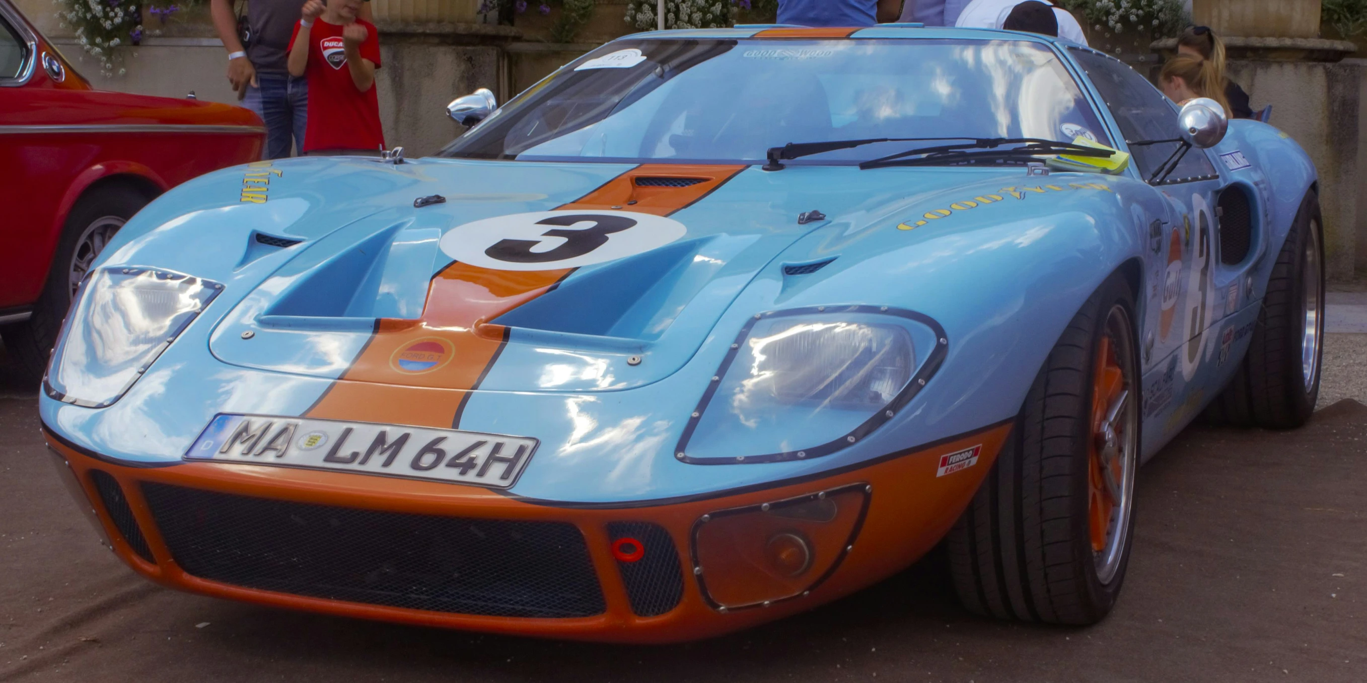 this blue sports car is sitting in front of people