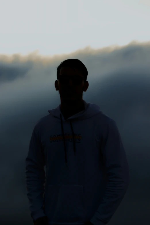 a silhouette of a man standing on a cloudy day