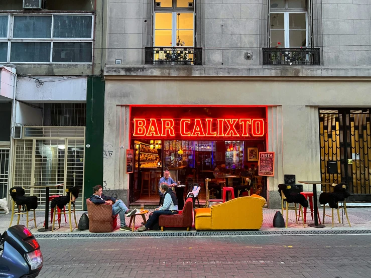 people sit at tables outside of a restaurant