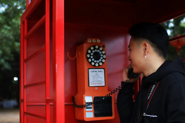 the woman is using a red phone outside