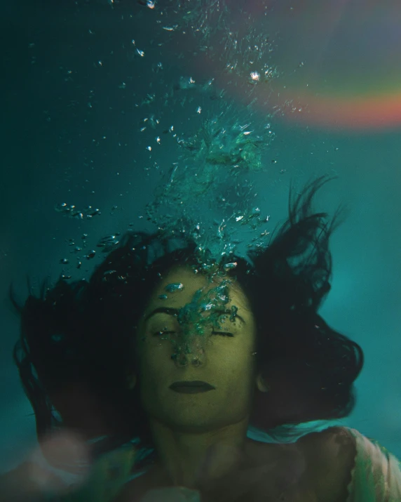 a woman is underwater and she has green paint on her face